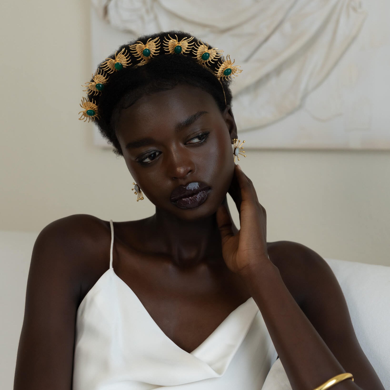 Woman wearing a decorative headpiece and white dress in a classical setting