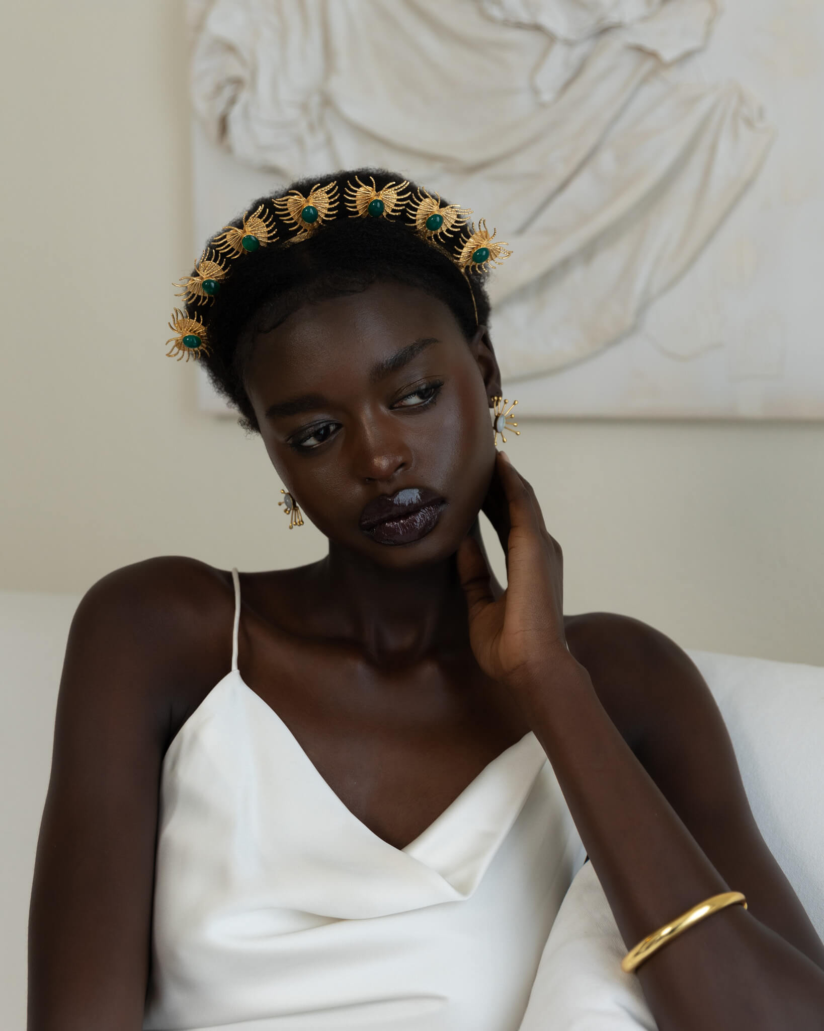 Woman wearing a decorative headpiece and white dress in a classical setting