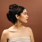 Woman wearing gold jewelry against a brown background