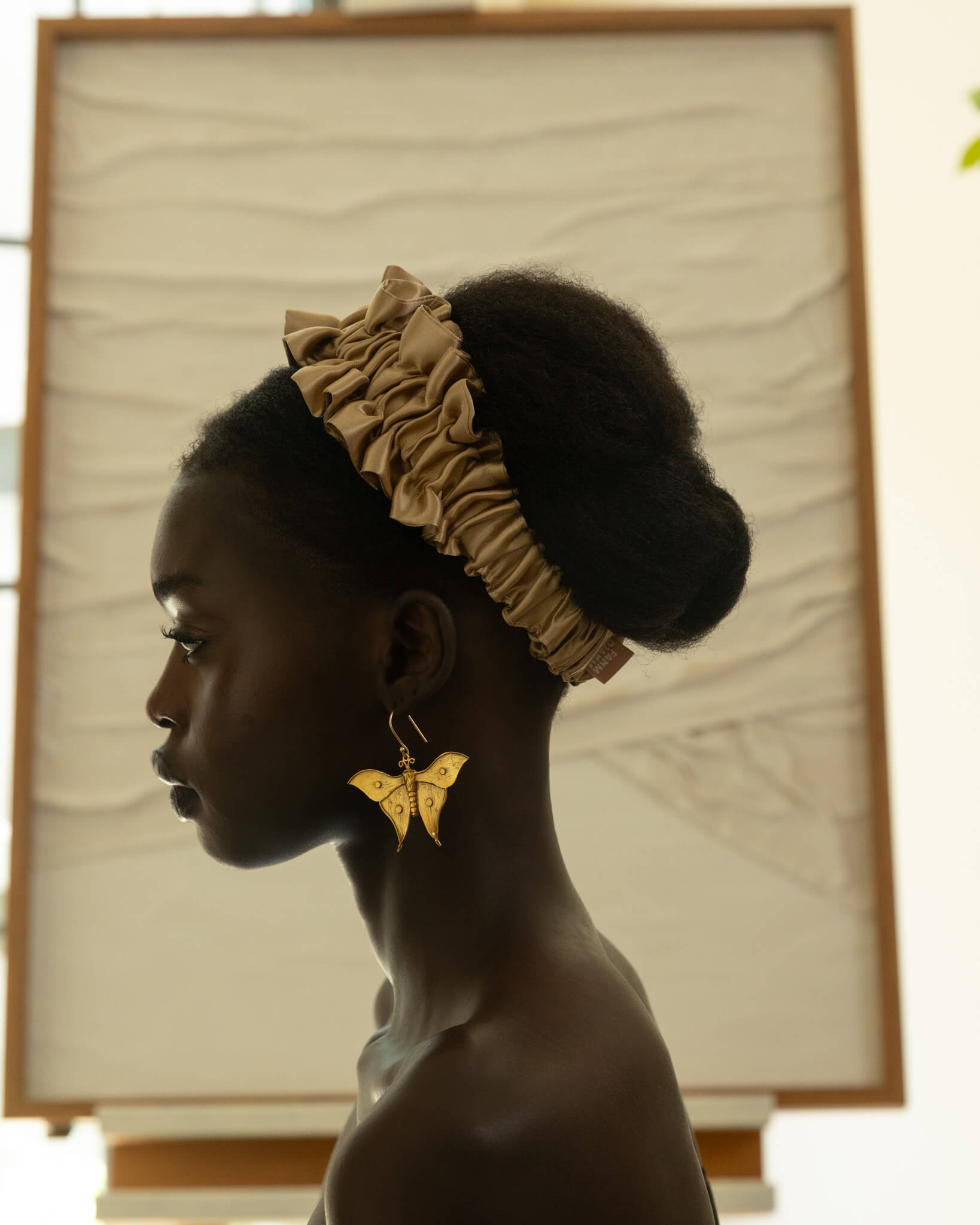 Woman wearing a gold headband and earrings with a blurred background