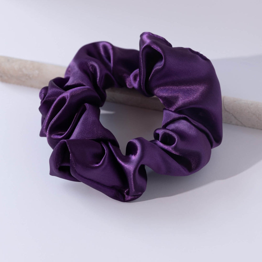 Purple satin scrunchie on a light gray background
